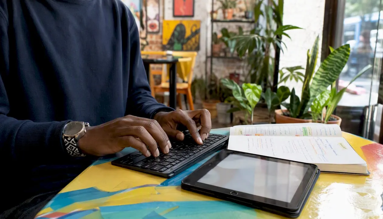 Hands typing with CRM feature papers on glass desk
