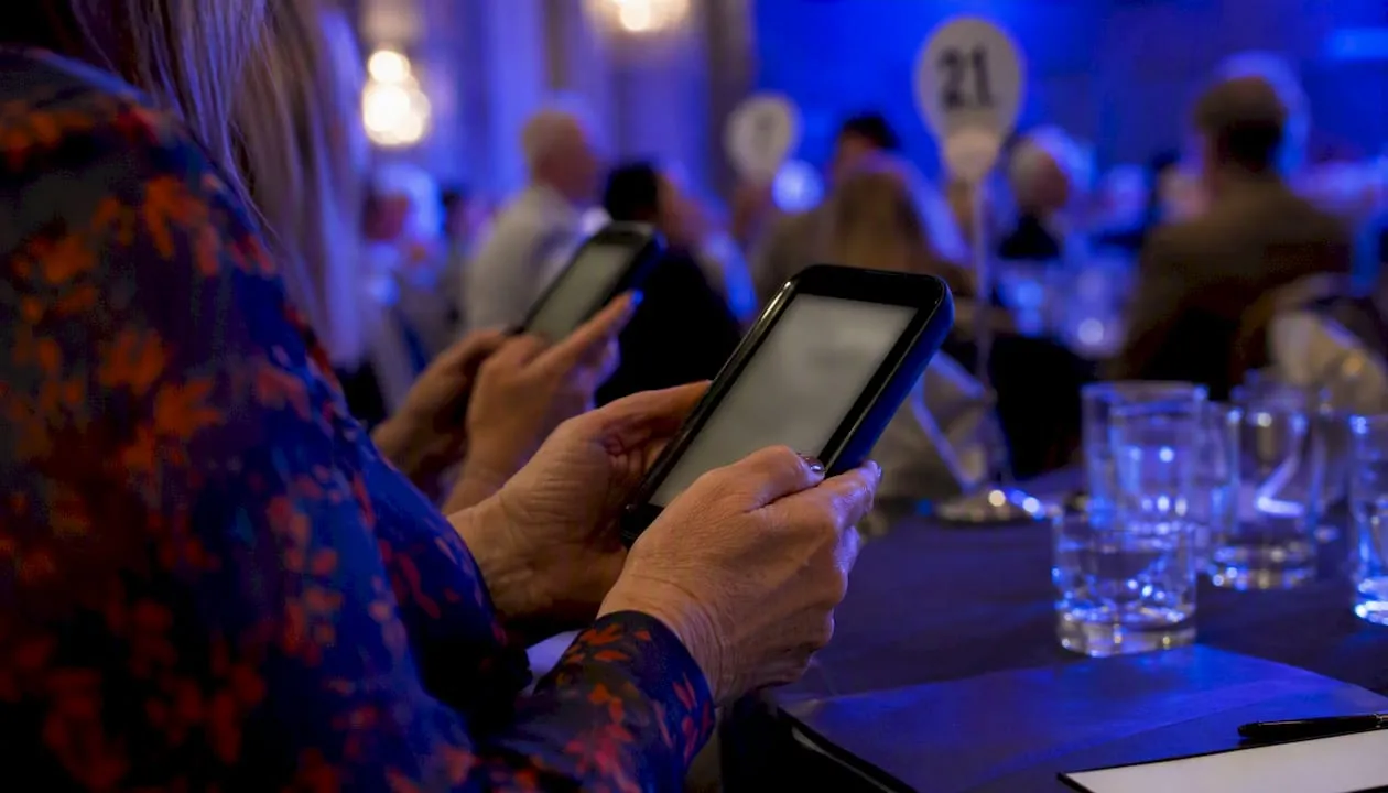 Hands using mobile devices at charity auction