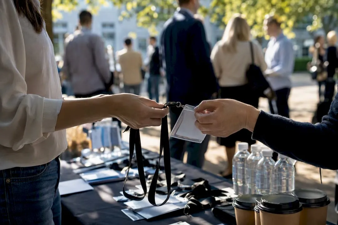 Hands exchanging alumni event badges outdoors